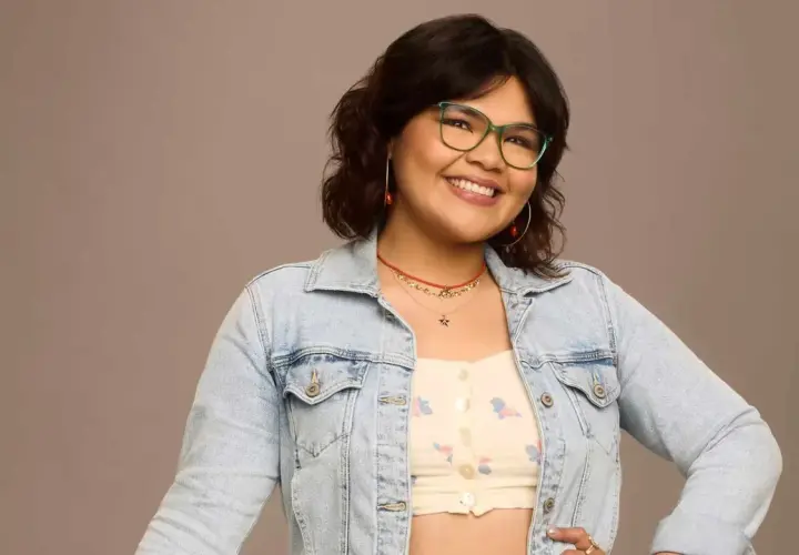 Belissa Escobedo, souriante, porte une veste en jean et des lunettes vertes. Elle est connue pour ses rôles dans des films et séries TV.