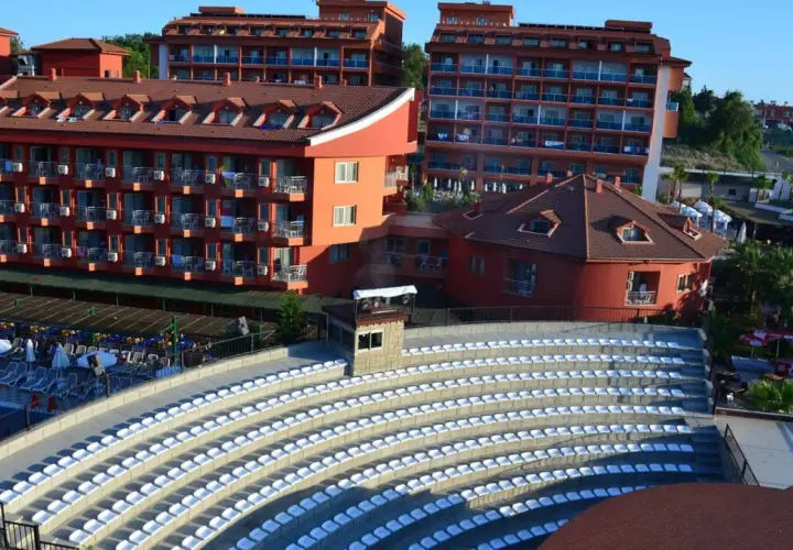 Amfiteatr z białymi siedzeniami i hotelami w tle, idealne miejsce na wieczorne pokazy w club side coast.