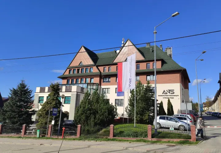 Budynek Akademii Nauk Stosowanych w Nowym Targu z polską flagą.