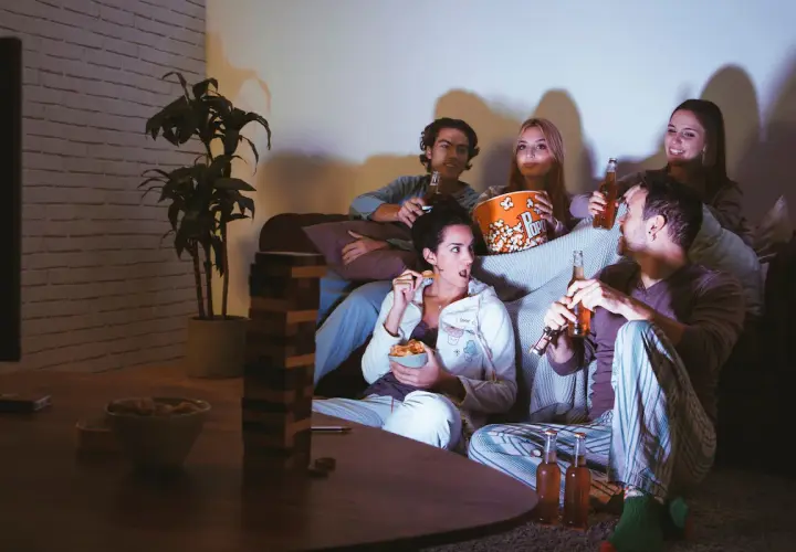 Ragazzi sul divano, popcorn e birra per una serata film.