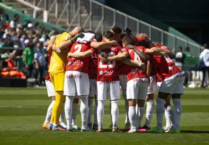 Piłkarze RCD Mallorca w czerwonych strojach tworzą zwarty krąg przed meczem z Valencią CF.
