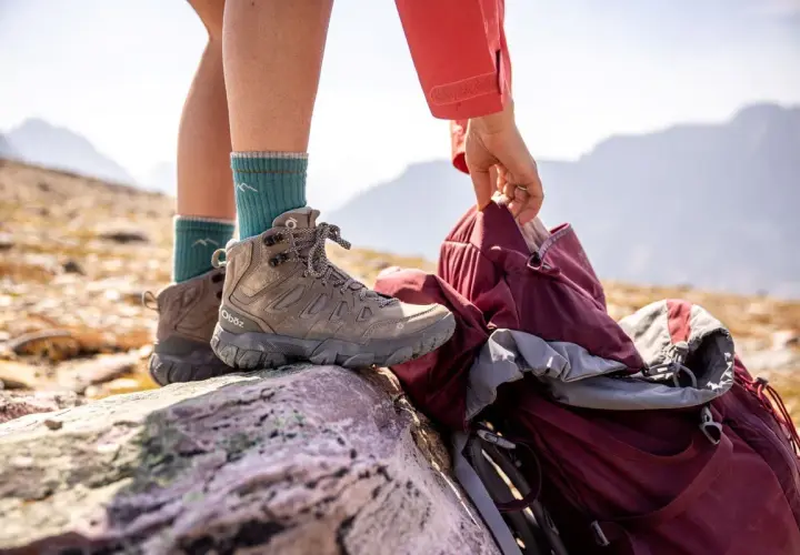 A hiker prepares for adventure, checking their boots. Are boots sized differently than shoes? These sturdy Oboz boots are ready for the trail.