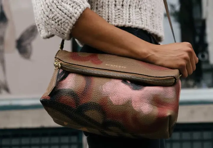 Torba Burberry z motywem moro, przykład brytyjskich marek odzieżowych, noszona przez kobietę w swetrze.