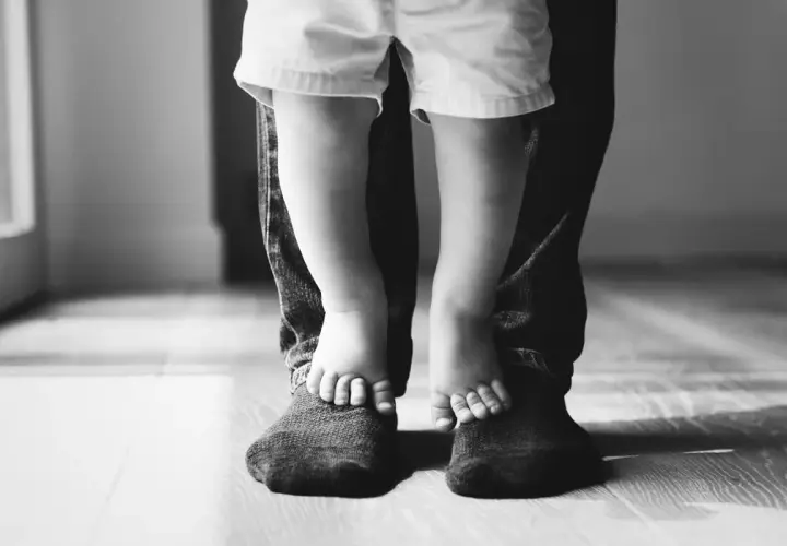 Piedini di bimbo su quelli del papà. Un abbraccio di gambe, un legame forte. Mia figlia preferisce il papà separato, ma i loro piedi uniti raccontano un amore che non si spezza.