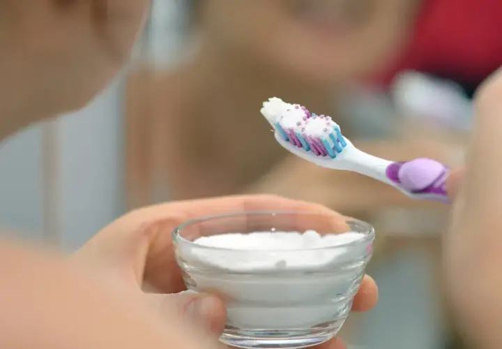 Mano tiene una spazzolino con dentifricio e una ciotola con polvere bianca, forse per sbiancare i denti con perossido di idrogeno.