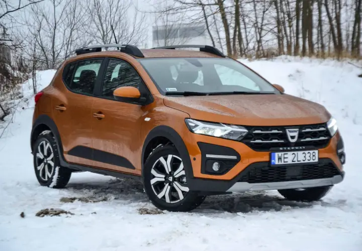 Pomarańczowy Dacia Sandero Stepway na śniegu, gotowy na zimowe wyzwania.