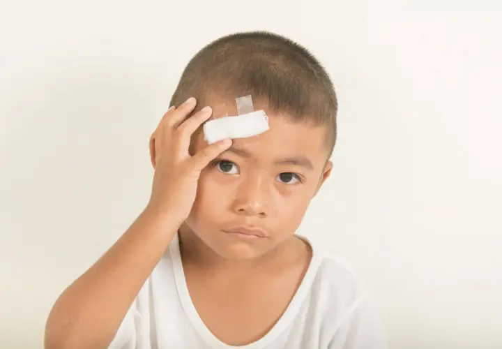 Bambino con cerotto sulla fronte, forse a seguito di un trauma cranico.