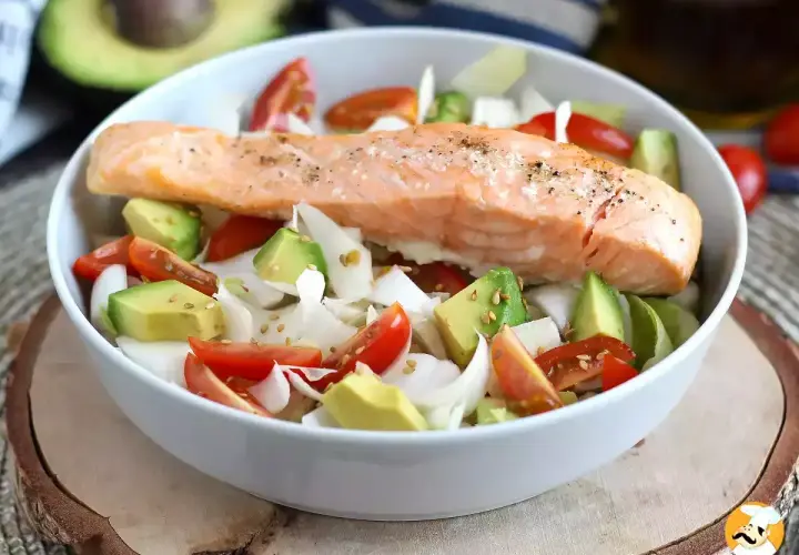 Delizioso filetto di salmone cotto su un letto di avocado, pomodorini e cipolla bianca. Un piatto leggero e gustoso, perfetto come secondi di pesce.
