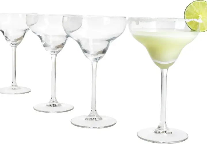 Cztery kieliszki do margarity, jeden z zielonym drinkiem i plasterkiem limonki, pozostałe puste.