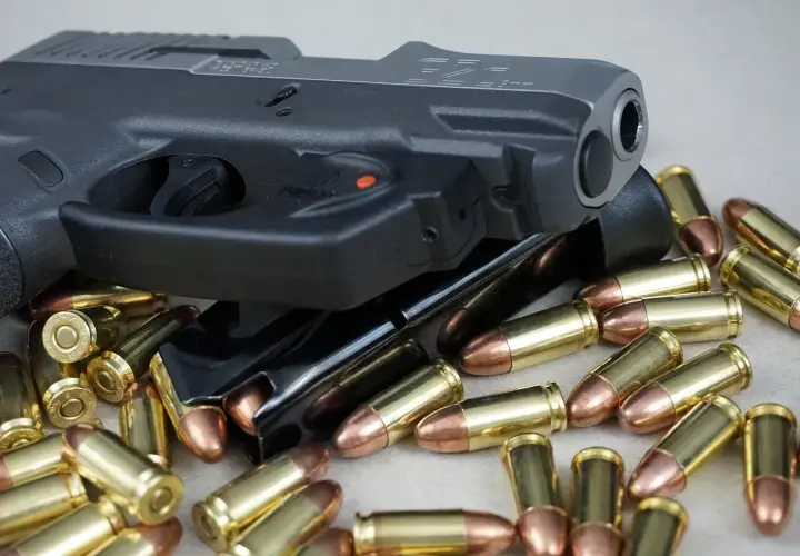 Pistolet i magazynki otoczone nabojami. Różne rodzaje pistoletów mogą być prezentowane w podobnych ujęciach.