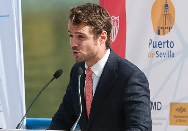 José María González de Caldas, con traje y corbata, habla en un atril con micrófonos. Fondo con logo de Puerto de Sevilla.