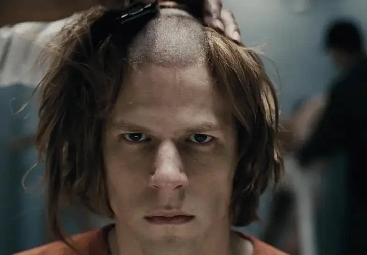 Un primo piano intenso di Jesse Eisenberg in un film, mentre gli rasano i capelli.