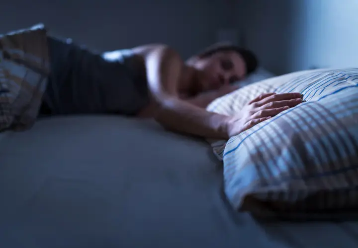 Persona durmiendo, mano sobre almohada. ¿Qué significa soñar con tu padre fallecido?