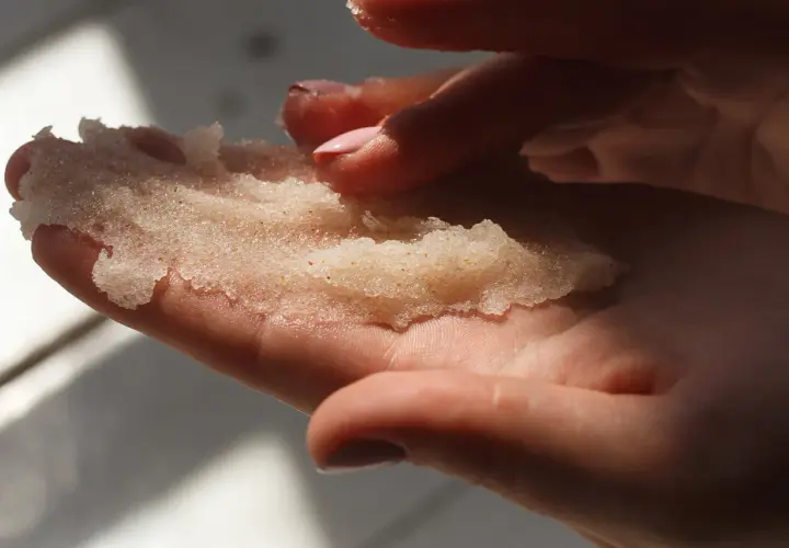 Dłonie trzymające domowy peeling cukrowy. Delikatne drobinki kuszą do domowego SPA.