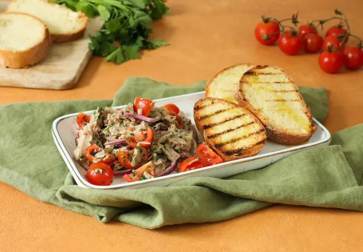 Deliziosa insalata di bollito con pomodorini, cipolla rossa e pane abbrustolito, un piatto fresco e saporito.