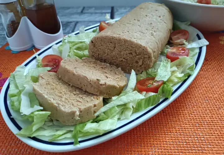 Un gustoso polpettone di tonno, affettato e servito su un letto di lattuga fresca con pomodorini.