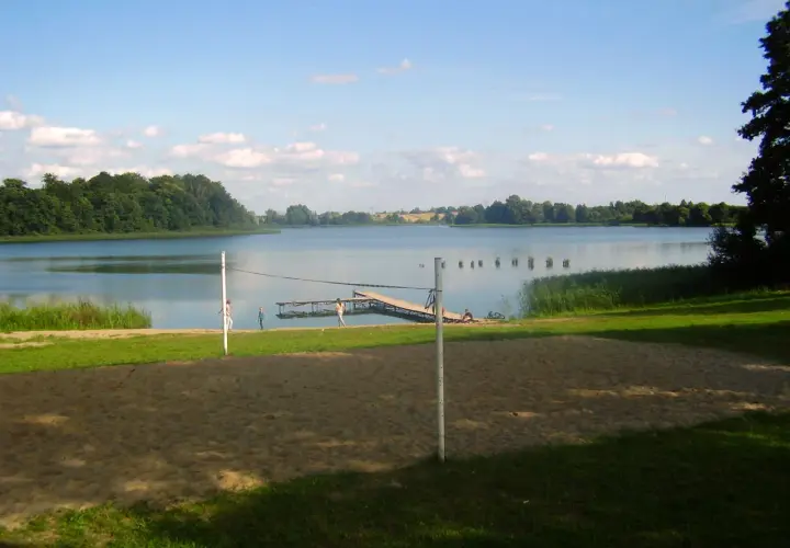 Piękny dzień nad jeziorem Skiertąg. Plaża, molo i zielone drzewa tworzą idylliczny krajobraz.