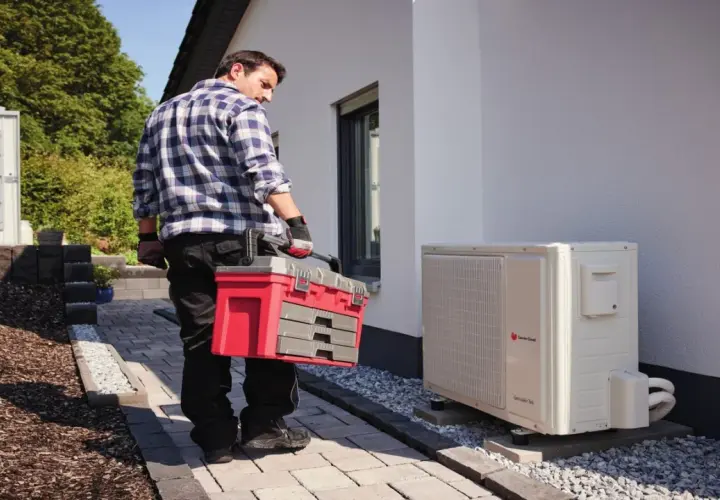 Technik z walizką narzędziową przy pompie ciepła. Regularny przegląd pompy ciepła zapewnia jej sprawność.
