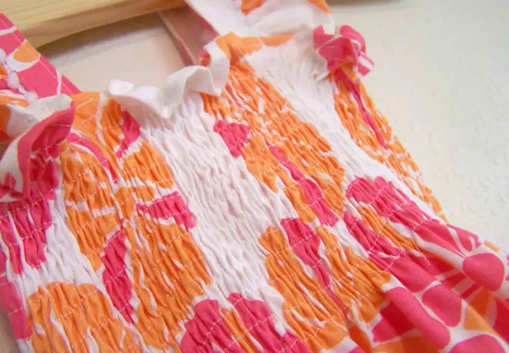 Close-up of a smocked garment with a floral pattern, showing how to sew with elastic thread for a gathered effect.