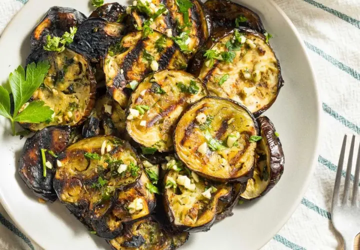 Rodajas de berenjenas a la plancha, doradas y tiernas, con ajo picado y perejil fresco. Un plato sencillo y delicioso.