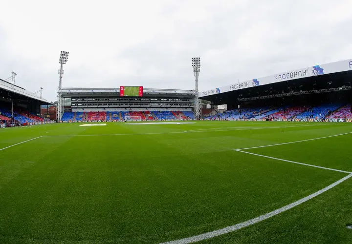 Zielona murawa stadionu Selhurst Park, trybuny w kolorach czerwonym i niebieskim, światła masztów.