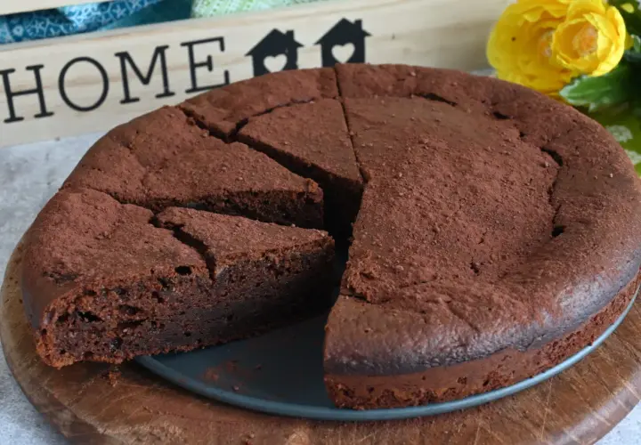 Un invitante dolce al cioccolato, cosparso di cacao, pronto per essere gustato. Sullo sfondo, una decorazione con la parola "HOME" e fiori gialli.