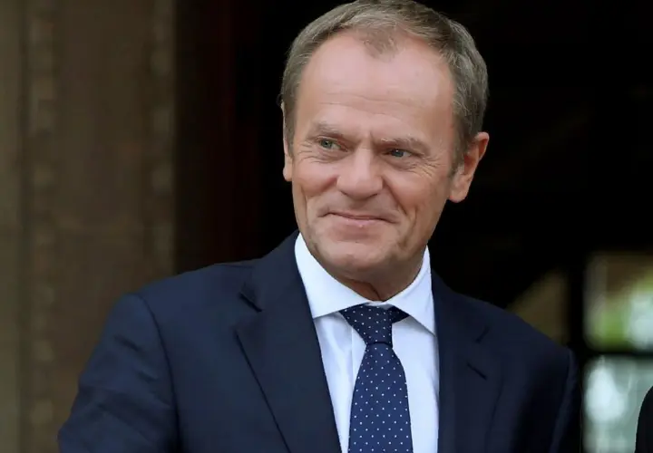 Donald Tusk w garniturze i krawacie, uśmiecha się.