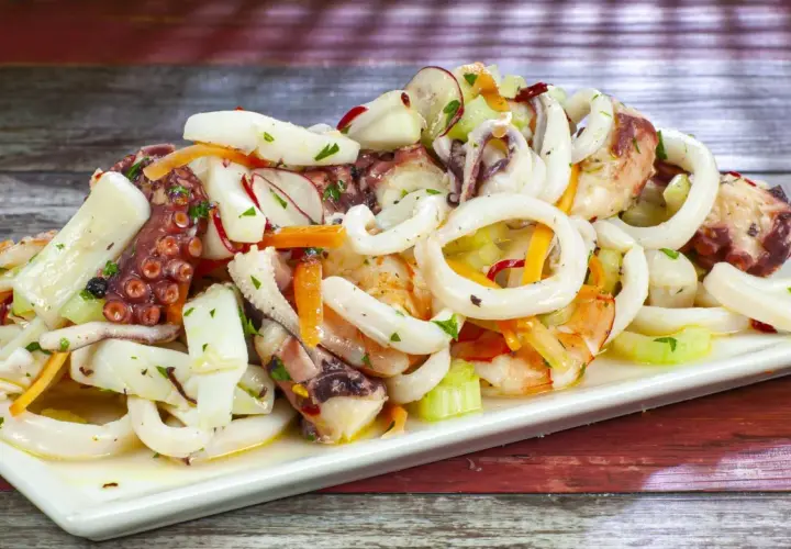 Deliziosa insalata di mare con anelli di calamaro, tentacoli di polpo e gamberi, condita con verdure fresche.