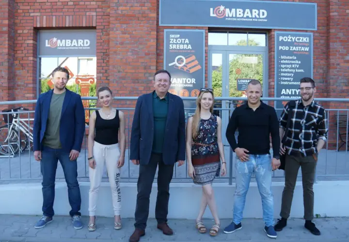 Lombard życie pod zastaw obsada: uśmiechnięci pracownicy lombardu pozują przed budynkiem.