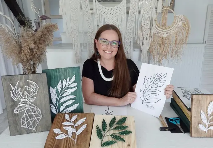 Kobieta prezentuje swoje prace string art, w tym jelenia i liście. Pokazuje też szablony do string art, które pomagają tworzyć piękne dekoracje.
