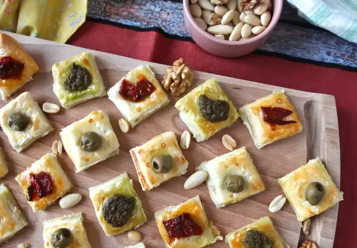 Pyszne przekąski francuskie z oliwkami, pesto i suszonymi pomidorami, ułożone na desce.