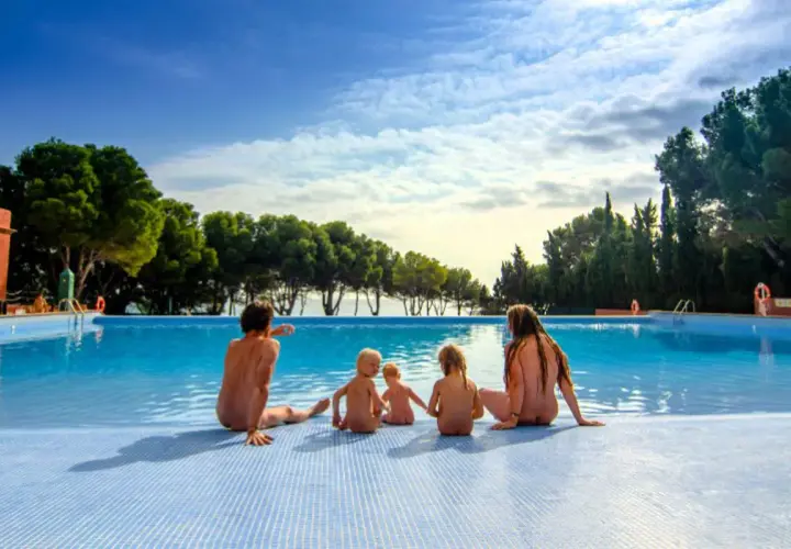 Famille profitant d'une journée ensoleillée au bord de la piscine dans un camping naturiste au Portugal.