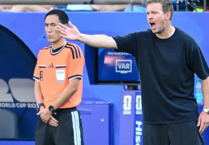 Trener Niemiec gestykuluje, dyskutując z arbitrem podczas meczu.