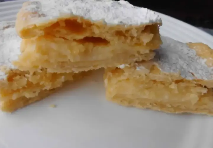 Kruche ciasto przełożone kremem, posypane cukrem pudrem. To smak dzieciństwa, czyli napoleonka przepis babci.