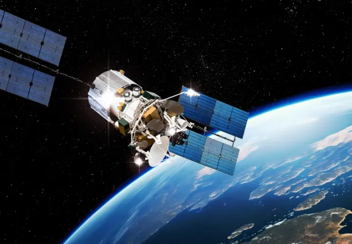 Satelita z dużymi panelami słonecznymi krąży nad Ziemią. Widać jego skomplikowaną konstrukcję i antenę.