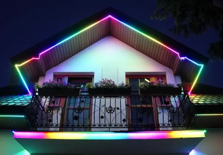 Kolorowy led w podbitce domu tworzy tęczową iluminację dachu i balkonu, nadając nocnej fasadzie magiczny wygląd.