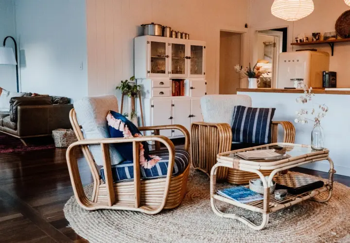 Wnętrze w stylu boho: wiklinowe fotele, stolik, kanapa i biała komoda.