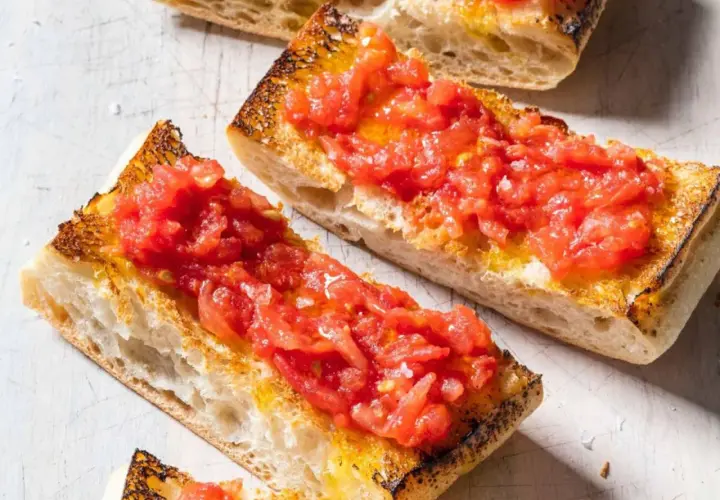 Rebanadas de pan tostado cubiertas con tomate rallado y aceite de oliva, un delicioso pan tumaca.