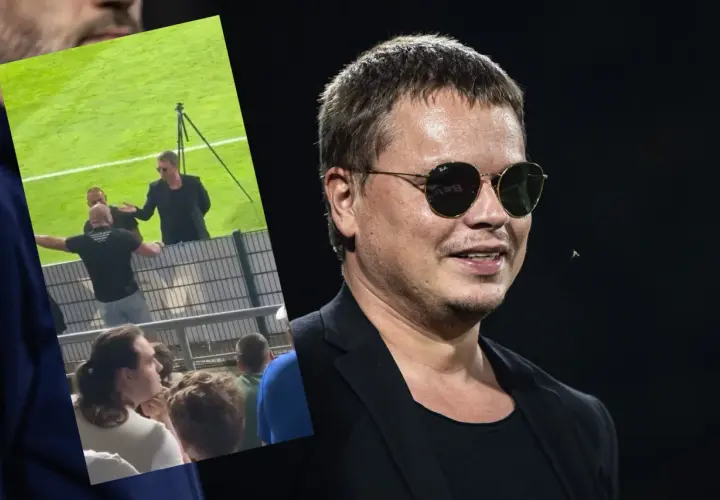 Właściciel Wisły Kraków w okularach przeciwsłonecznych, na tle fragmentu stadionu i kibiców.