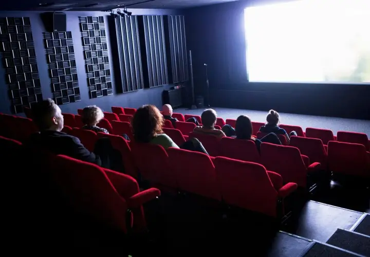 Publiken sitter i röda biosalongsstolar och tittar på en ljus bioduk. Klara biografen är redo för filmvisning.
