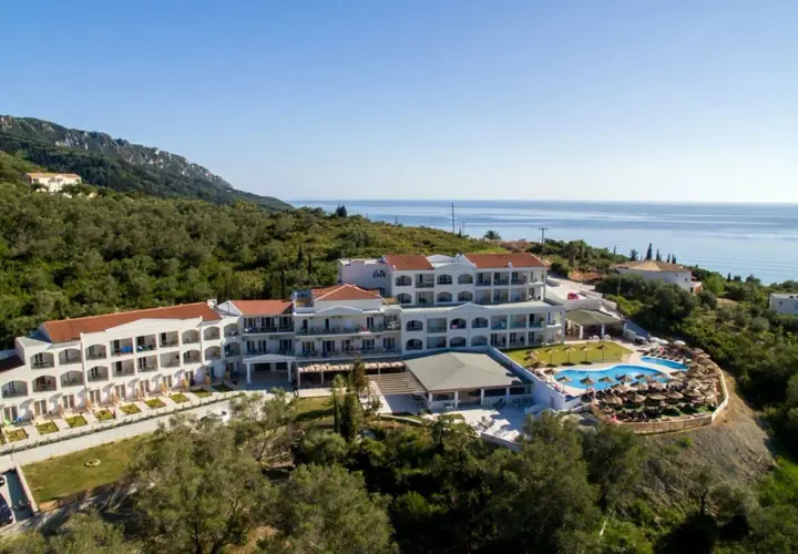 Hotel Saint George Palace z basenem i widokiem na morze, otoczony zielenią.