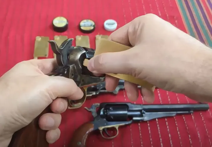 Dłonie przygotowują rewolwer do strzału, używając kapiszonów Remington No. 10.