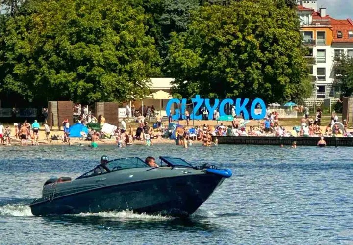Motorówka sunie po wodzie, obok plaży w Giżycku. Idealne miejsce na odkrywanie mazurskich szlaków wodnych.