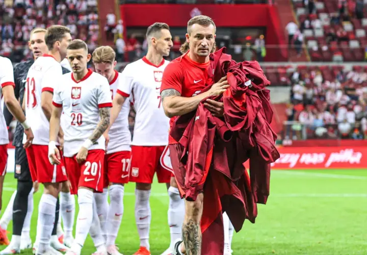 Piłkarze reprezentacji Polski schodzą z boiska. Na pierwszym planie Grzegorz Krychowiak, który trzyma w rękach bordową bluzę. Kim jest Krychowiak? To doświadczony pomocnik, który grał w wielu klubach.