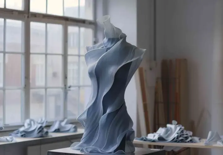 Sculpture en tissu bleu, aux formes fluides et ondulantes, évoquant une robe de haute couture. Une création d'art inspirée par l'IA mode.