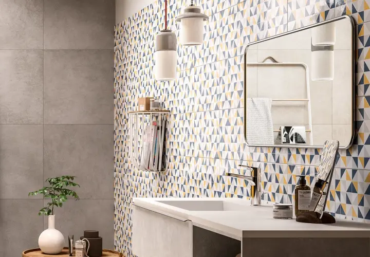 Un bagno moderno con piastrelle geometriche colorate che coprono le pareti. Un lavandino minimalista e un grande specchio completano l'arredo.