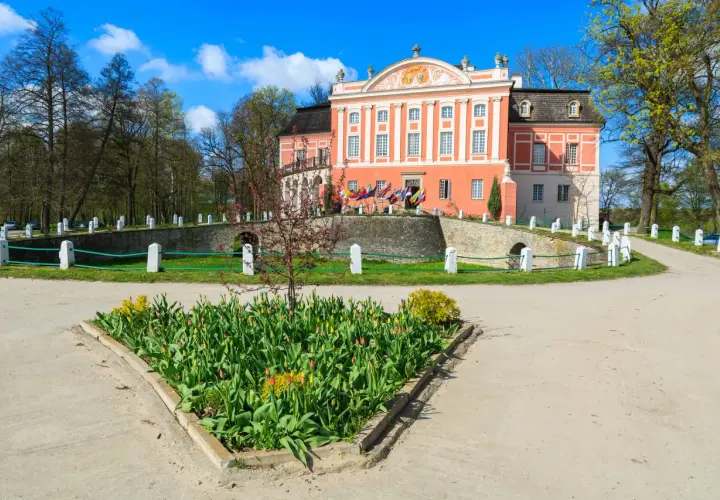 Kurozwęki atrakcje: barokowy pałac otoczony parkiem, z kwitnącymi tulipanami przed wejściem.