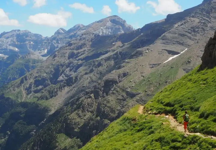 Senderista en un camino escarpado con vistas a las majestuosas montañas de Ordesa Monte Perdido.