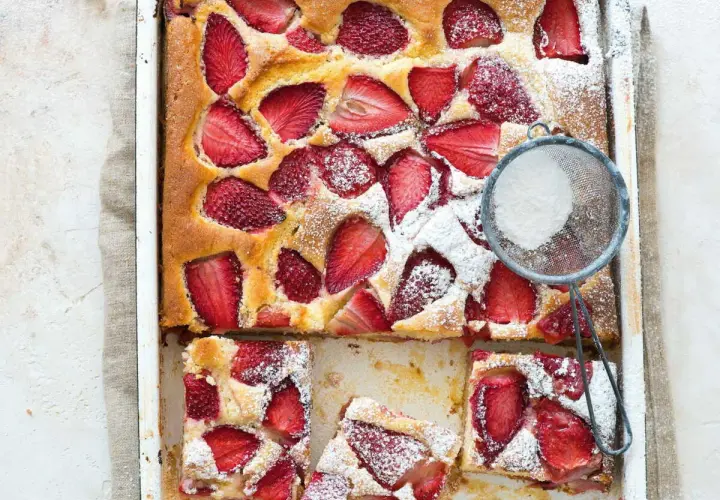 Le gâteau aux fraises de maman, doré et garni de fruits rouges, est saupoudré de sucre glace. Un délice !