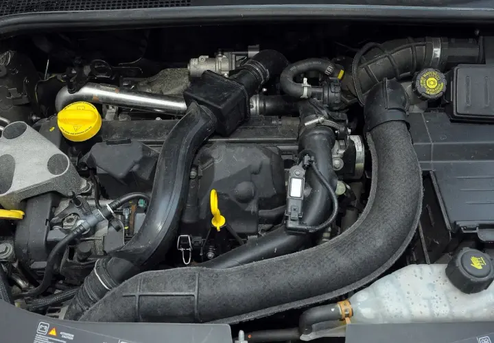 Silnik Renault Clio 3 z widocznymi przewodami, czujnikami i żółtym korkiem oleju.